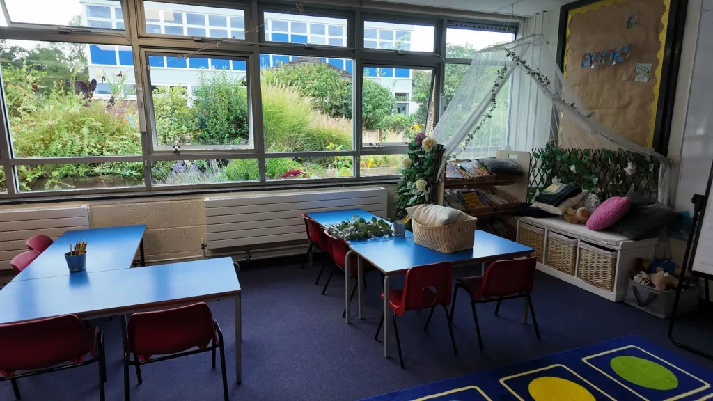 Primary school classroom with tables, chairs and a reading area