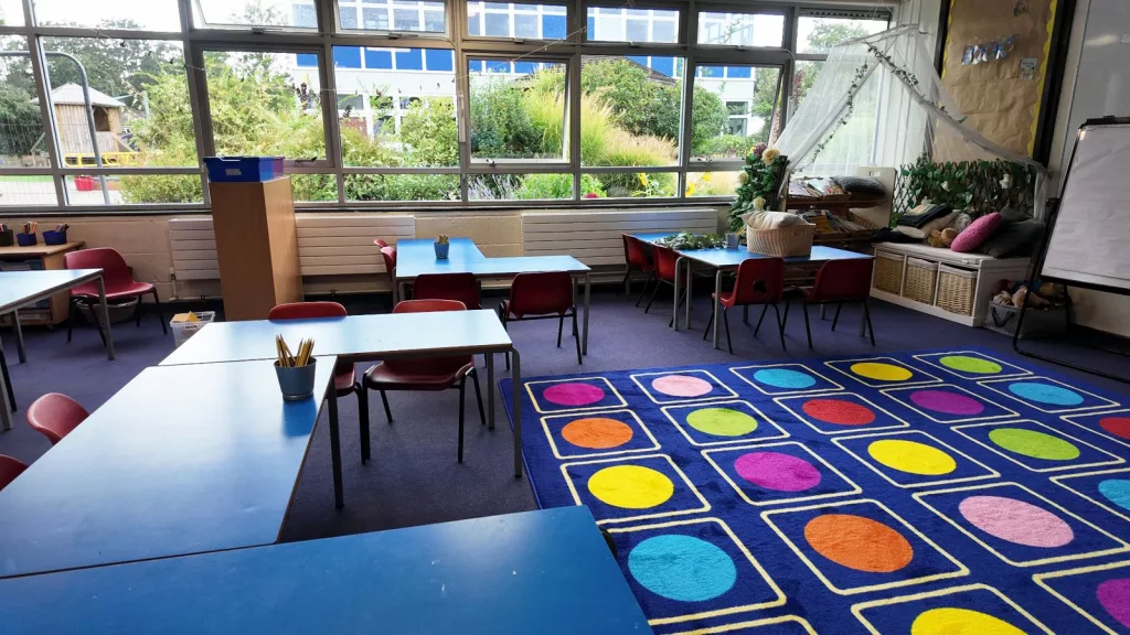 Primary school classroom with tables, chairs and a reading area