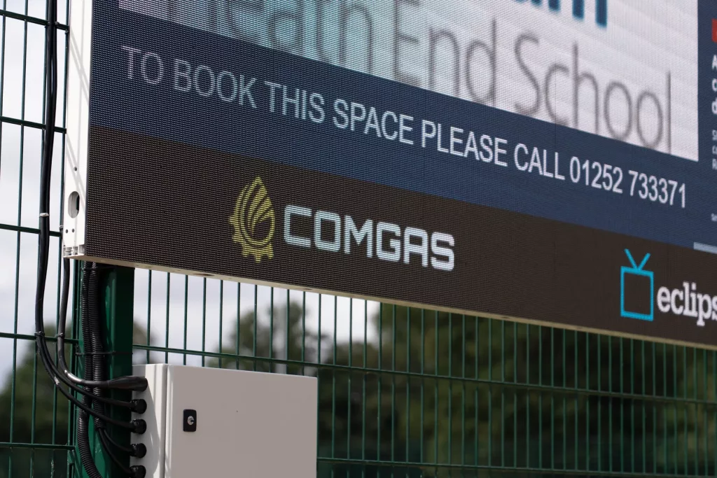 ComGas branding and electrical enclosure beneath the Farnham Heath End School LED screen