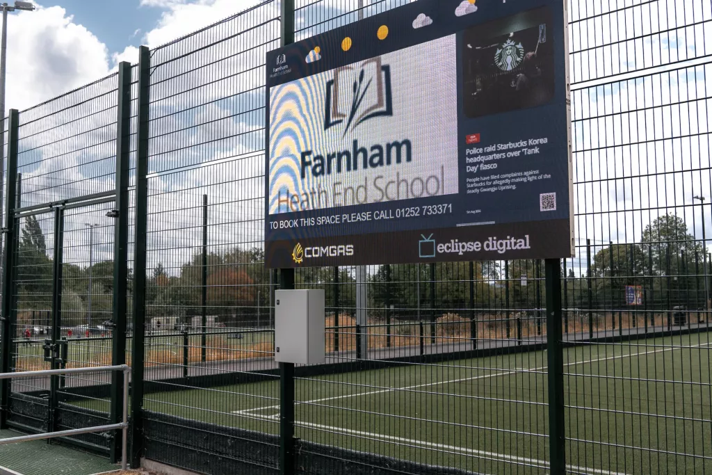 Angled view of the LED screen beside Farnham Heath End School’s all-weather sports pitches