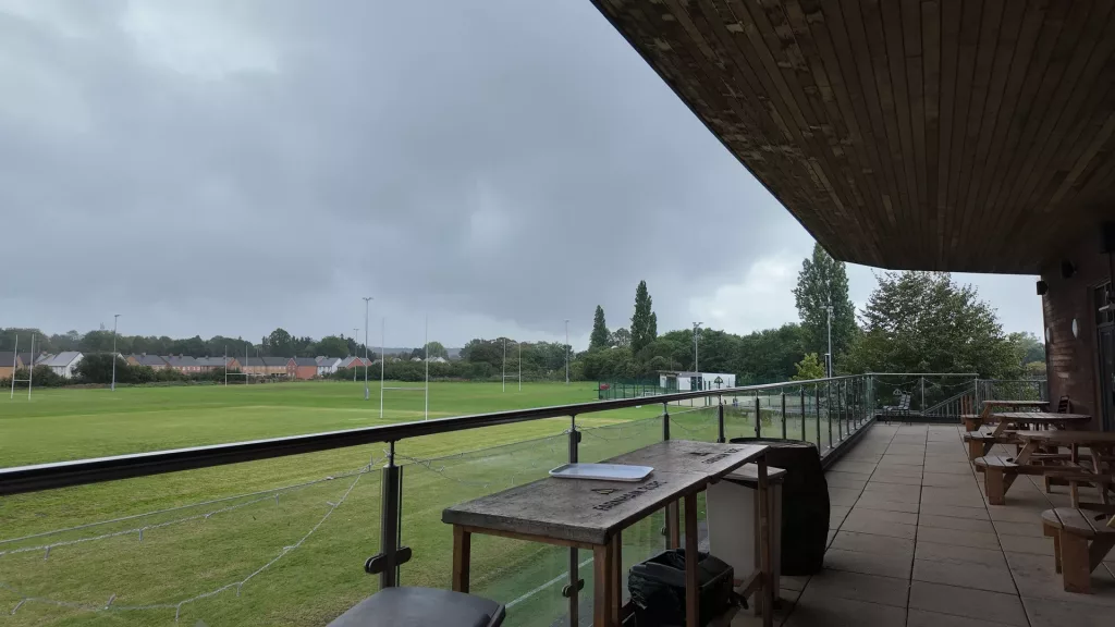 View from beneath the Farnham Rugby Club clubhouse balcony across the pitches and floodlights