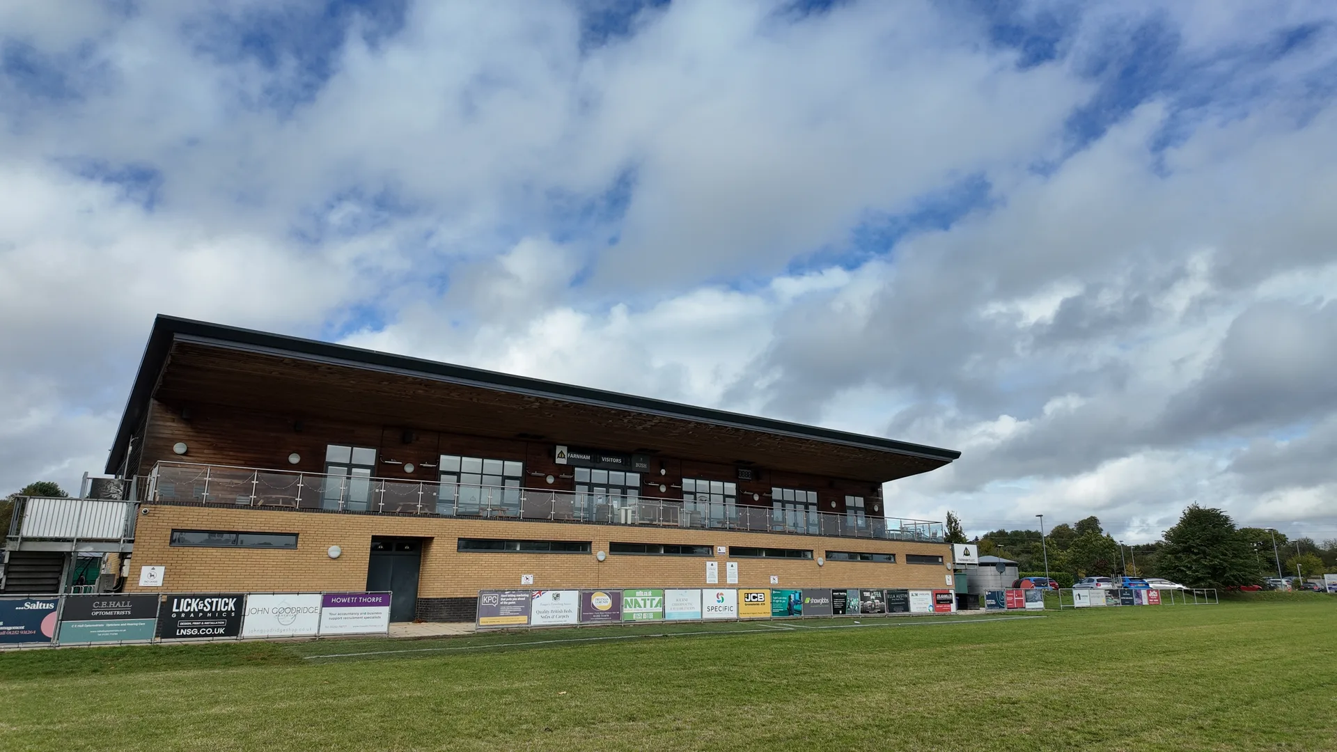 Farnham Rugby Club clubhouse seen from the main pitch, with pitchside sponsor boards along the front