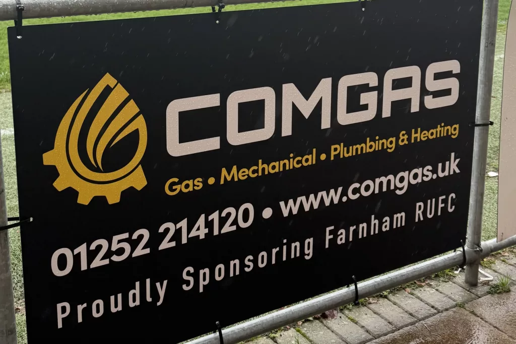 ComGas sponsor board at Farnham Rugby Club reading Proudly Sponsoring Farnham RUFC