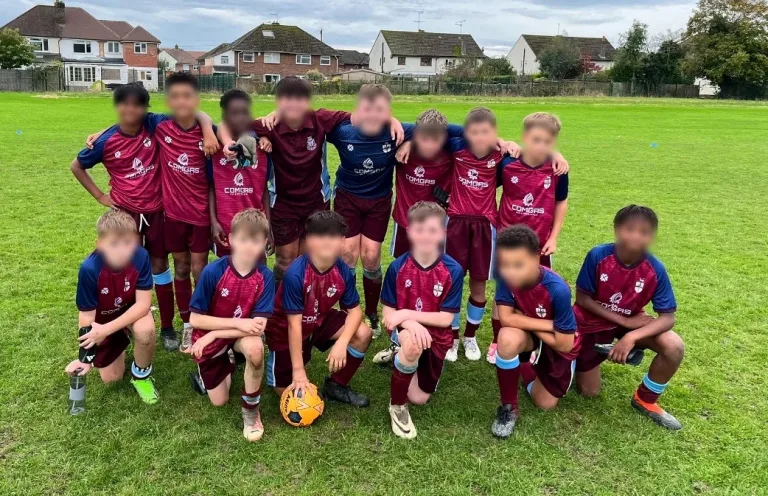 All Hallows Catholic School football team wearing ComGas-sponsored maroon and navy kit on the school playing field