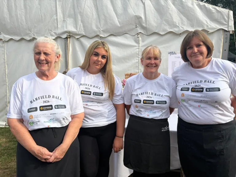 Four people in Barfield Ball 2026 shirts carrying sponsors’ logos, including ComGas