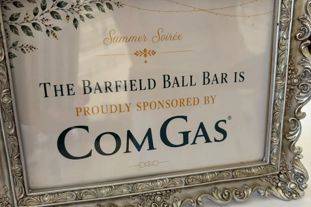 Framed sign at the Barfield Summer Ball reading The Barfield Ball Bar is proudly sponsored by ComGas