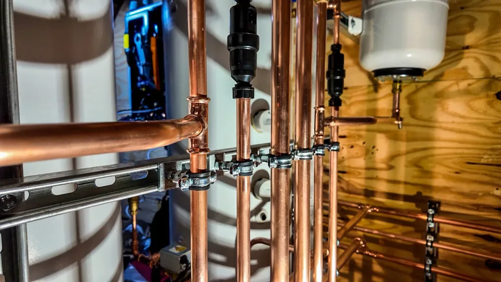 Close-up of supported copper pipework with pipe clips, isolation valves and strainers within the plant area