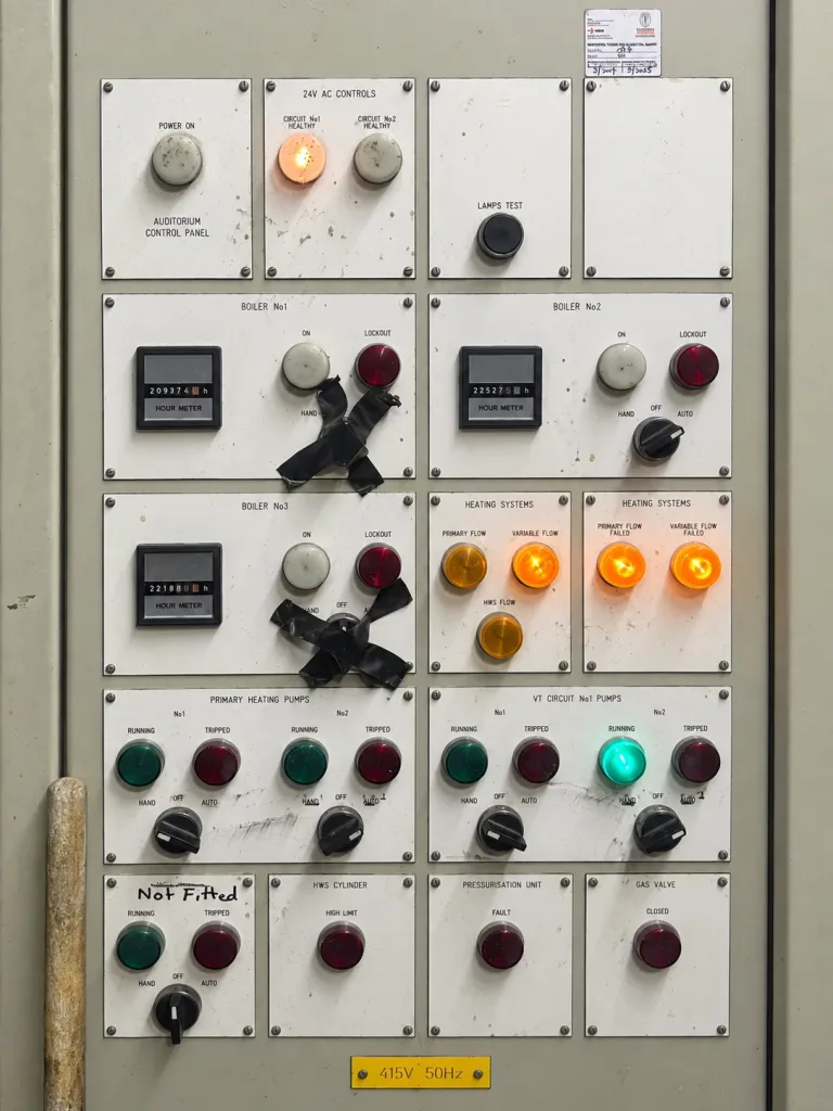 The original boiler control panel, showing worn labelling and taped-over controls