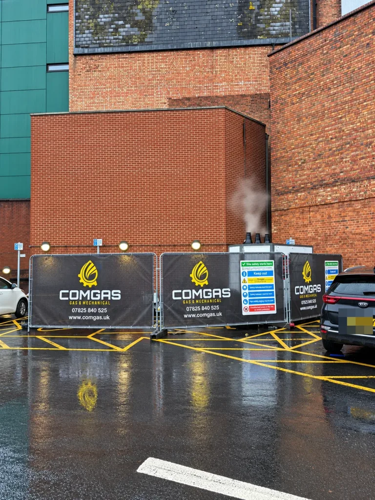 Temporary boiler installation behind ComGas site fencing in the car park beside the theatre
