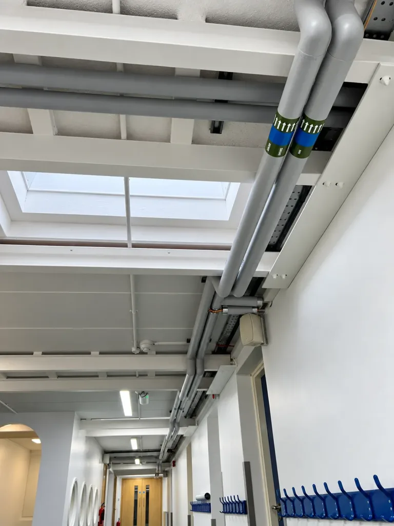 Completed school corridor with heating pipework, containment and lighting reinstated at high level