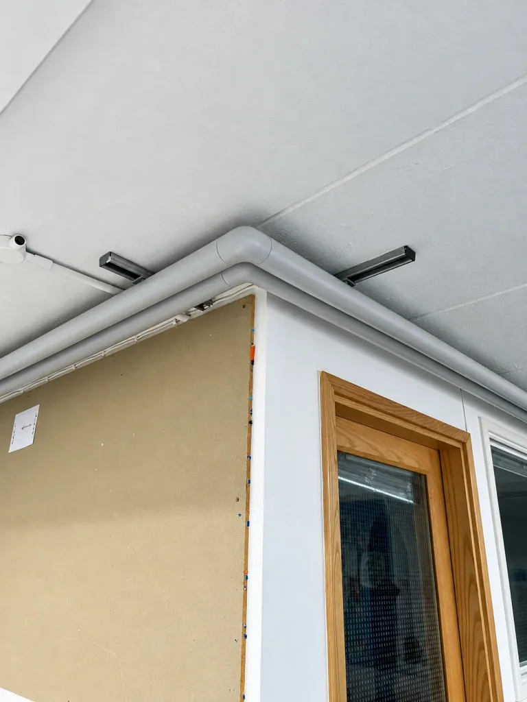 Close view of high-level pipework turning a corner above a corridor partition