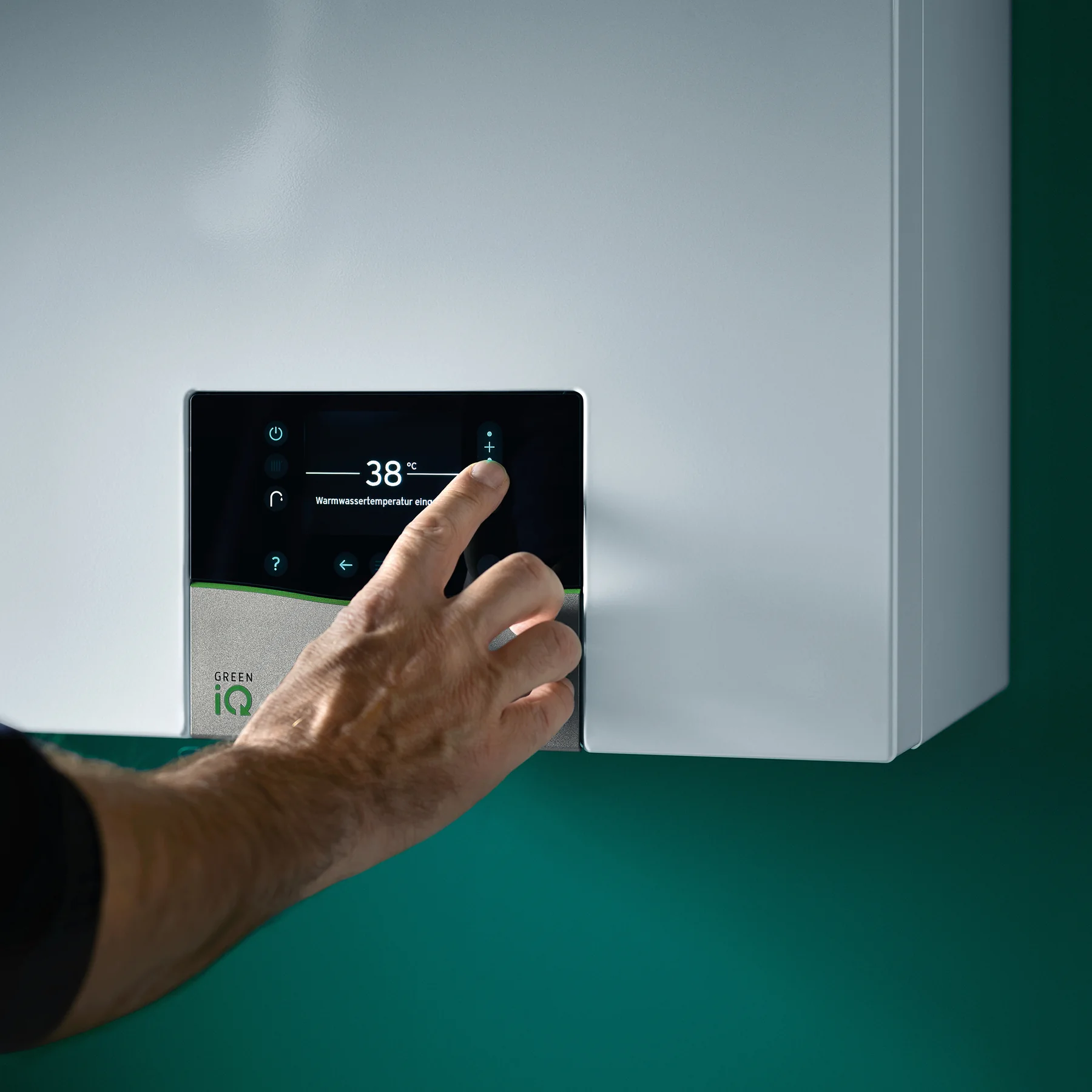 Hand using the control panel of a wall-hung Vaillant gas boiler to check the hot water temperature setting